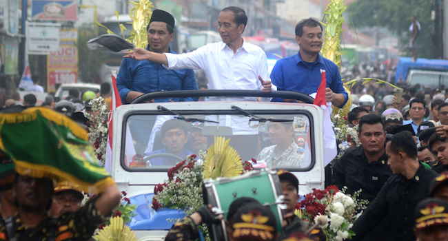 Former president Joko ‘Jokowi’ Widodo (center), alongside Central Java gubernatorial candidate pair Ahmad Luthfi (right) and Taj Yasin (left), distributes T-shirts during a campaign parade on Jl. Tegal in Purwokerto, Central Java, on 16 November 2024. (Antara/Oky Lukmansyah)